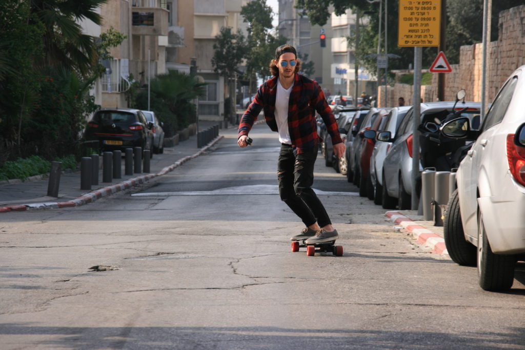riding an electric longboard on the street to work